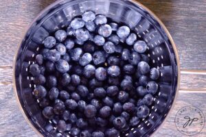A metal strainer filled with washed blueberries.