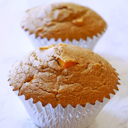 Two Butternut Squash Muffins in a row on a white, marble surface.