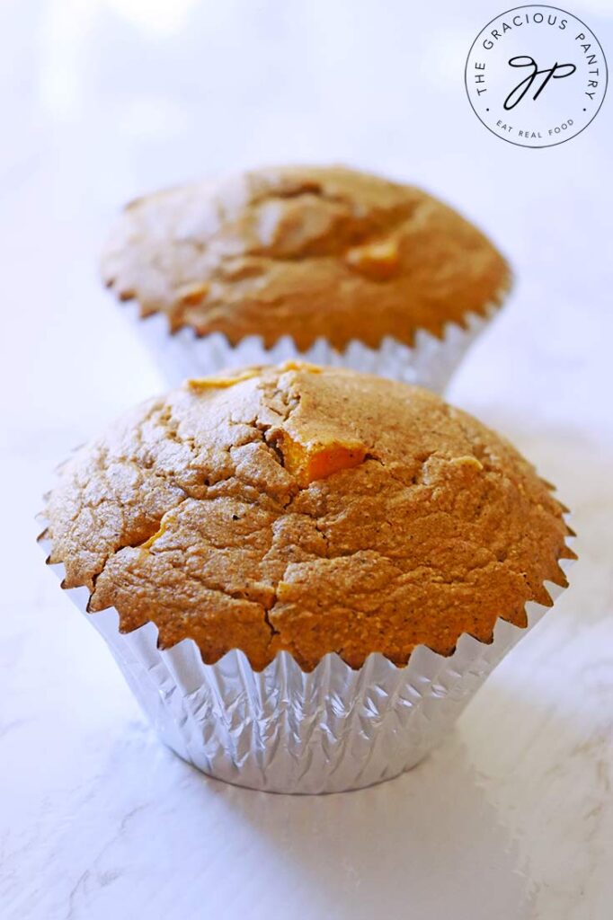 Two Butternut Squash Muffins in a row on a white, marble surface.
