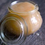 A jar filled with this Coconut Caramel. The lid rests against the side of the jar.