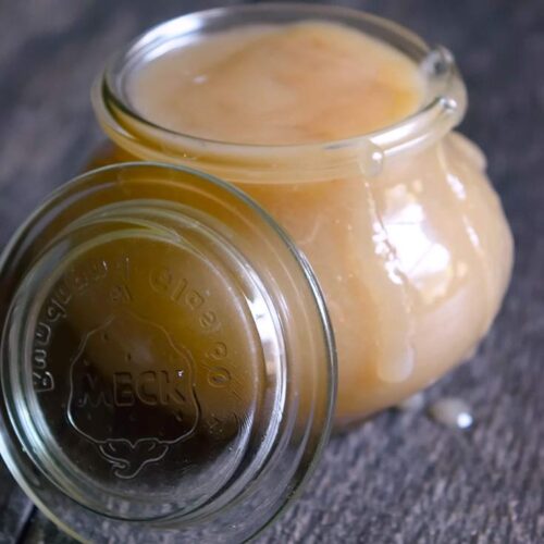 A jar filled with this Coconut Caramel. The lid rests against the side of the jar.