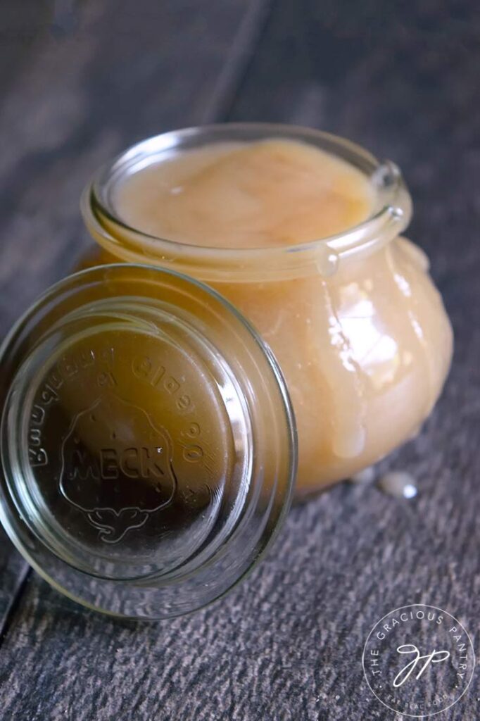 A jar filled with this Coconut Caramel. The lid rests against the side of the jar.