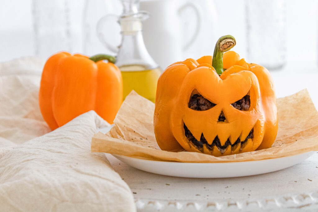 The finished Jack-O-Lantern Stuffed Peppers being served on a white platter.