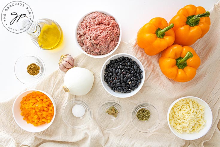 The ingredients for this Jack-O-Lantern Stuffed Peppers Recipe sitting on a white surface in separate, white bowls.