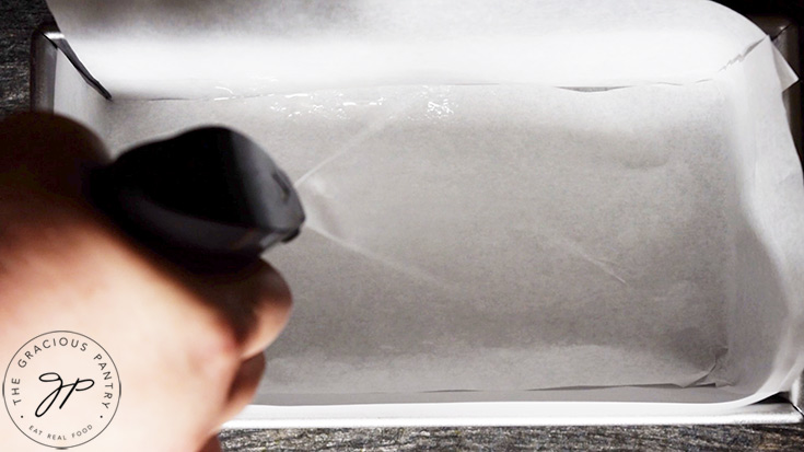 Spraying the loaf pan with an oil sprayer.