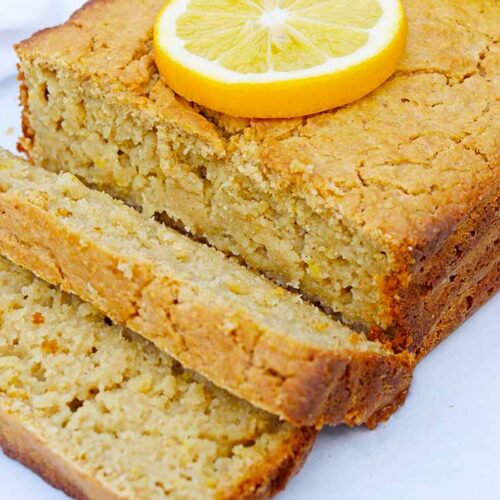 The loaf of Lemon Bread on a white background. Two slices are sliced at the front of the loaf.