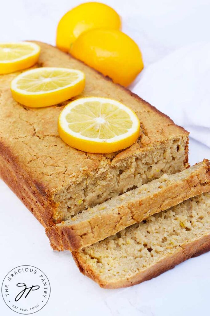 A sliced loaf of lemon bread with lemon slices garnishing the top of the uncut portion.