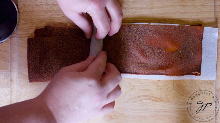 Rolling the Pumpkin Fruit Leather up in strips of parchment paper.