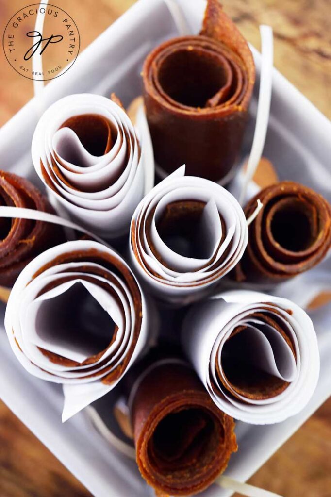 An overhead view looking down into a white basket of rolled fruit leathers.