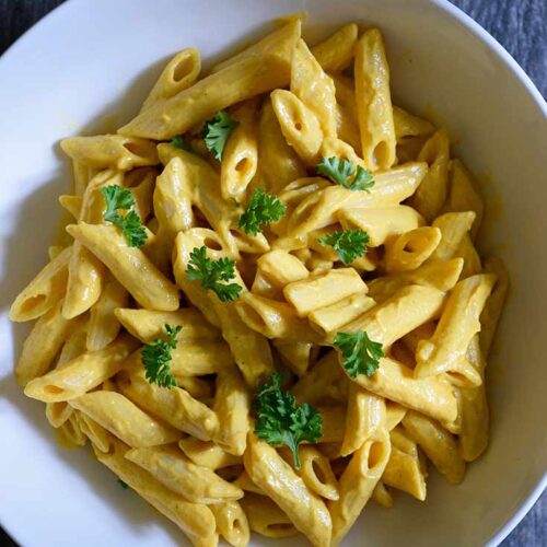 An overhead view looking down into a white bowl filled with pasta covered in this Pumpkin Pasta Sauce.