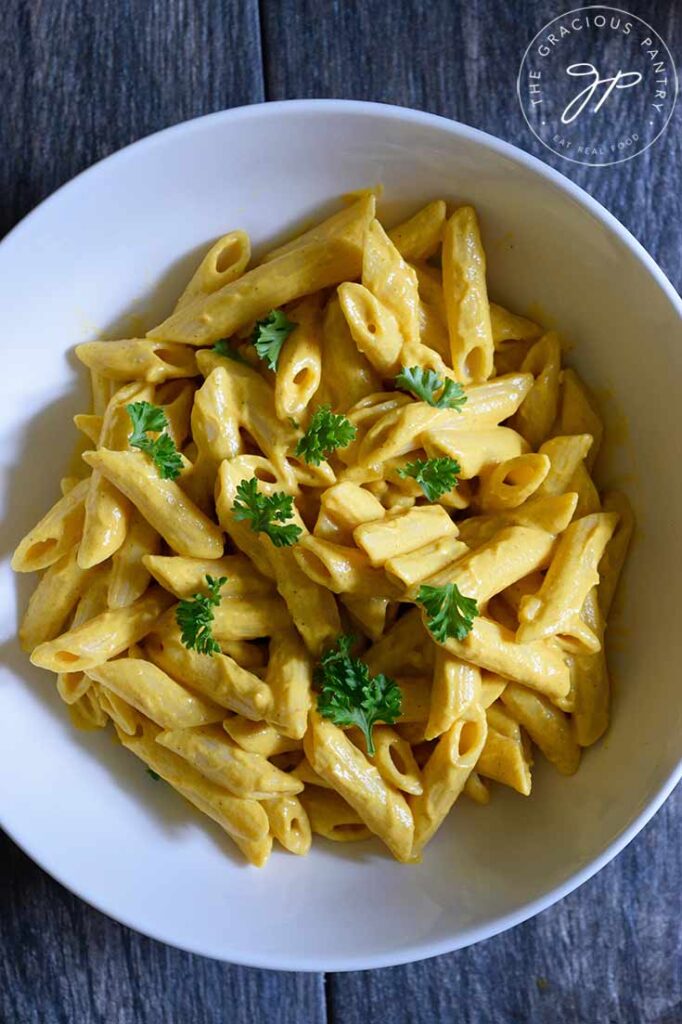 An overhead view looking down into a white bowl filled with pasta covered in this Pumpkin Pasta Sauce.