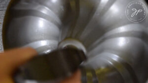 Spraying the bundt pan with oil.