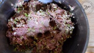 The meatball mixture kneaded together in a large mixing bowl.