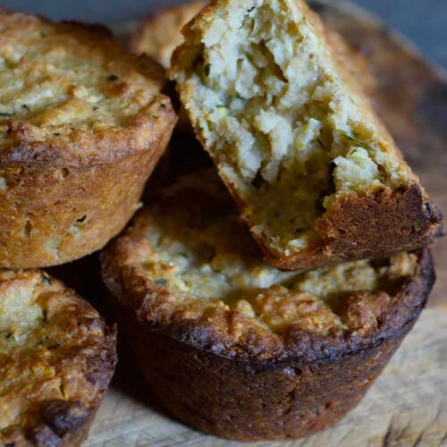 A close up of a stack of zucchini muffins with a bite taken out of one of them.