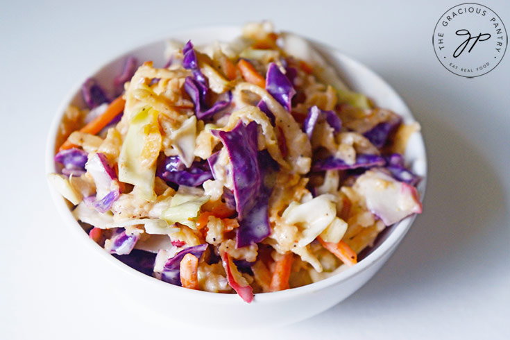 The finished Apple Slaw Recipe in a white bowl on a white background.