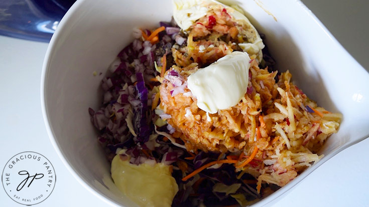 All the ingredients for this Apple Slaw Recipe in a large, white mixing bowl.