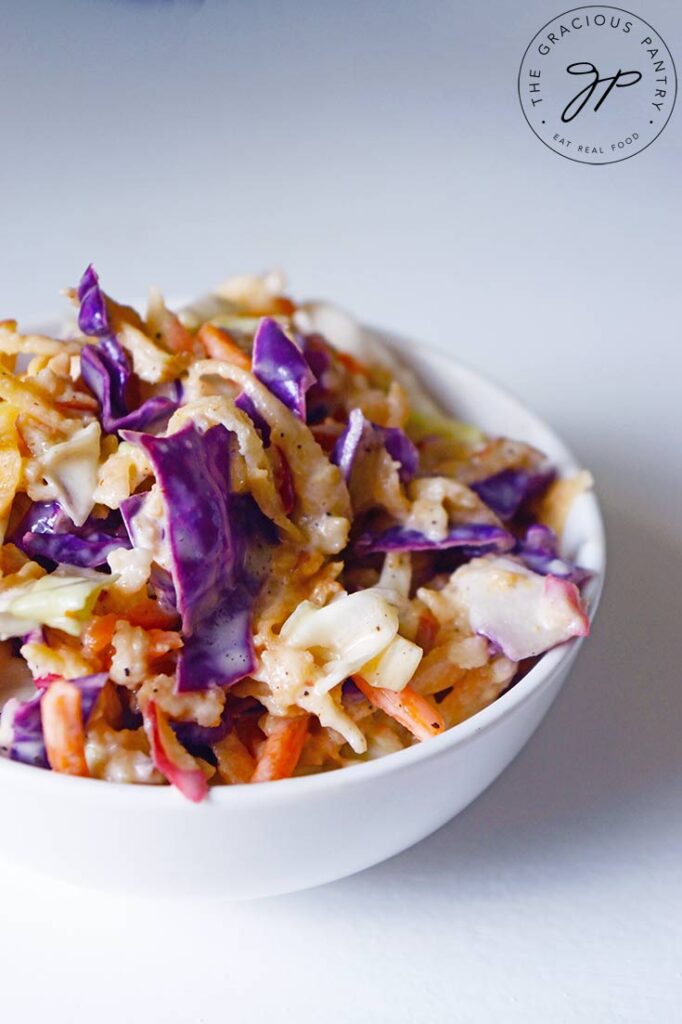 A side view of a white bowl filled with this Apple Slaw Recipe.