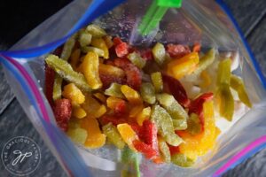 Frozen multi-color bell peppers added to the freezer bag.
