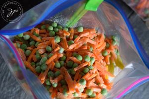Frozen peas and carrots added to the freezer bag.
