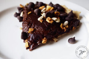 A horizontal, up close shot of a single slice of this Easy Homemade Chocolate Pie on a white plate.