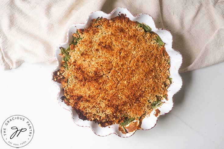 A golden brown, just baked Healthy Green Bean Casserole in a white, fluted casserole dish.