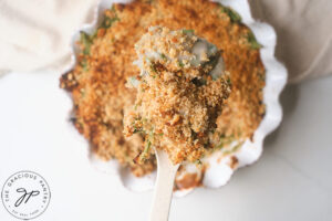 A serving spoon lifts some of this Healthy Green Bean Casserole Recipe towards the camera.