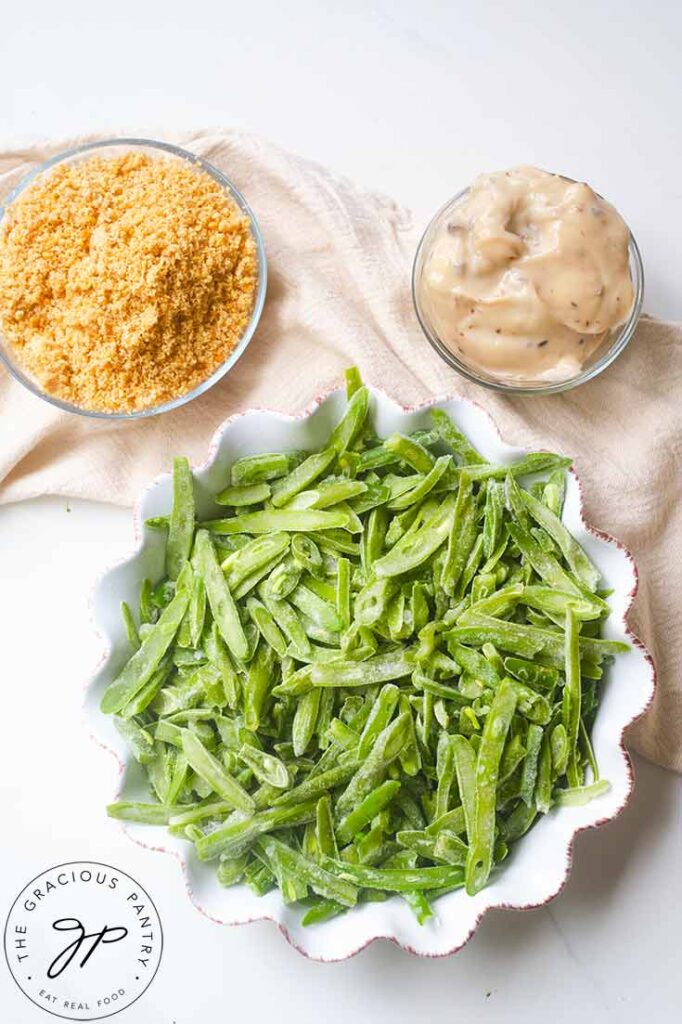 The ingredients for this Healthy Green Bean Casserole Recipe in individual bowls on a white table.