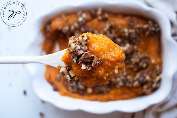 A spoon lifts a scoop of Healthy Sweet Potato Casserole towards the camera.