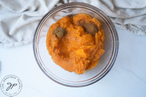 The mashed sweet potatoes and some spices in a mixing bowl.