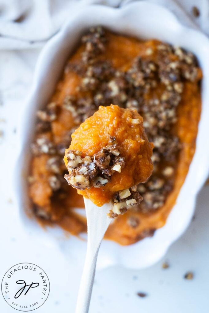 A spoon lifts a serving of Healthy Sweet Potato Casserole towards the camera.