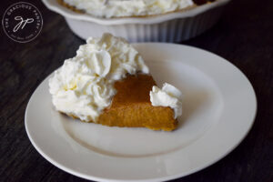 A single slice of Kabocha Pie served on a white plate and topped with whipped cream.