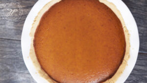 The finished kabocha pie, cooling after baking on a gray background.