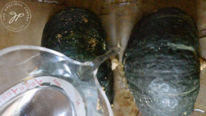 Pouring water into the baking pan with the squash.