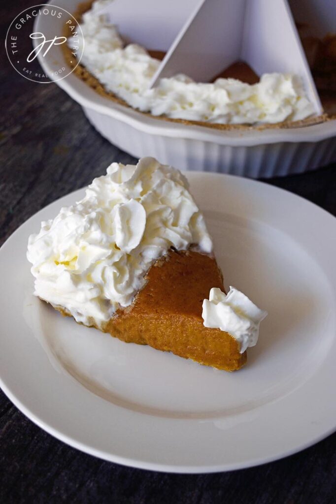A slice of Kabocha pie with whipped cream on a white plate.