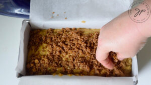 Sprinkling the topping over the raw batter in the loaf pan.