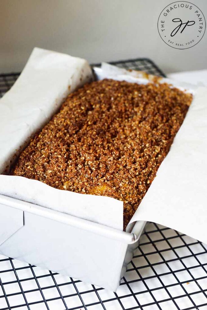 The full loaf of Snickerdoodle Pumpkin Bread in the loaf pan, cooling on a wire rack.