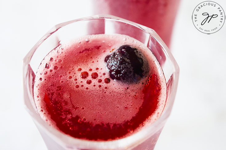 An up close shot of the top of a wine glass that is filled with this Cranberry Mimosa Mocktail Recipe.