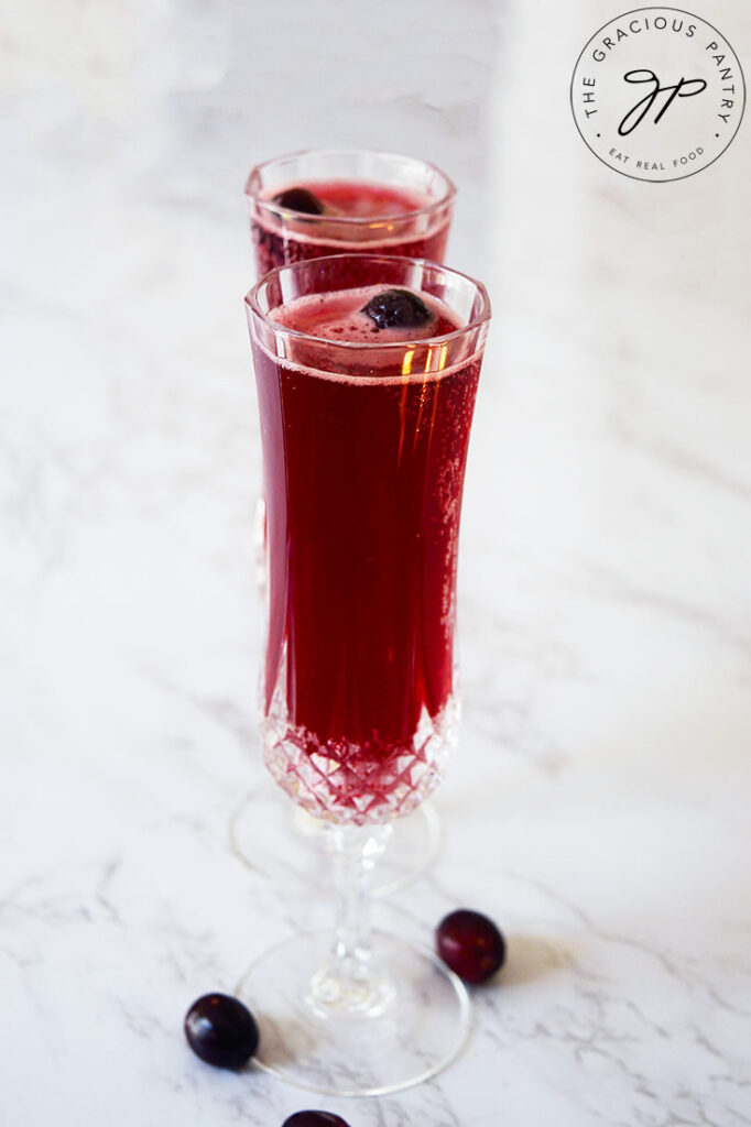 Two champagne glasses in a row, filled with Cranberry Mimosa Mocktail.
