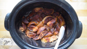 The cooked apples sitting in a black crock.