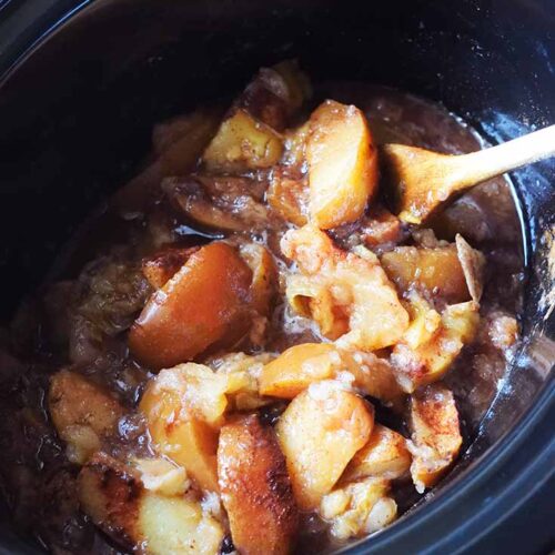 A black crock filled with just-cooked Crockpot Cinnamon Apples.