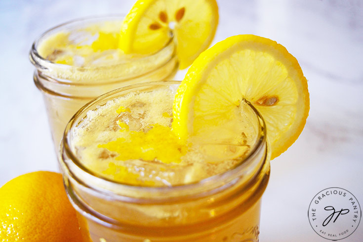 An up close view of the tops of two glass jars, filled with Lemon Drop Mocktail and garnished with lemon slices.