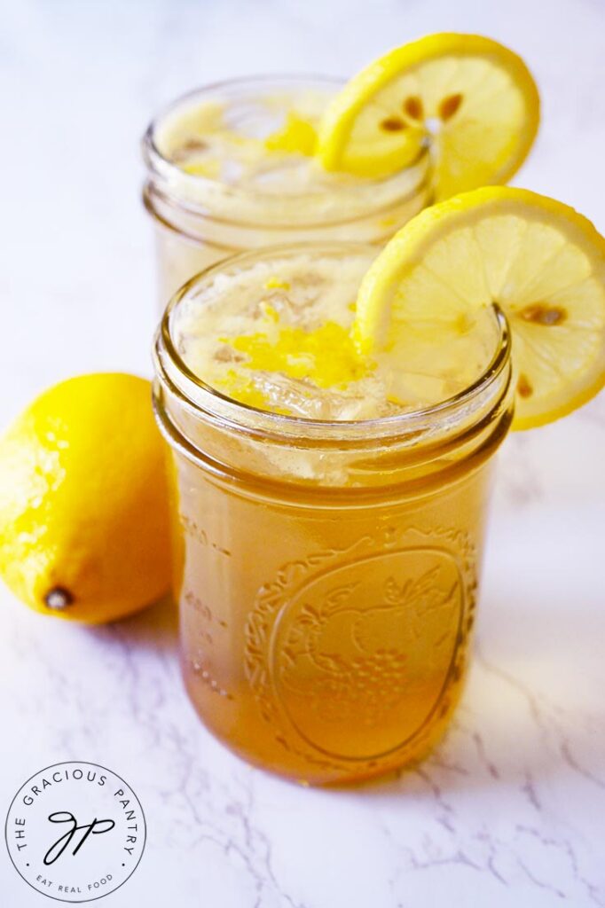 A vertical shot of two glasses filled with Lemon Drop Mocktail and garnished with lemon slices.