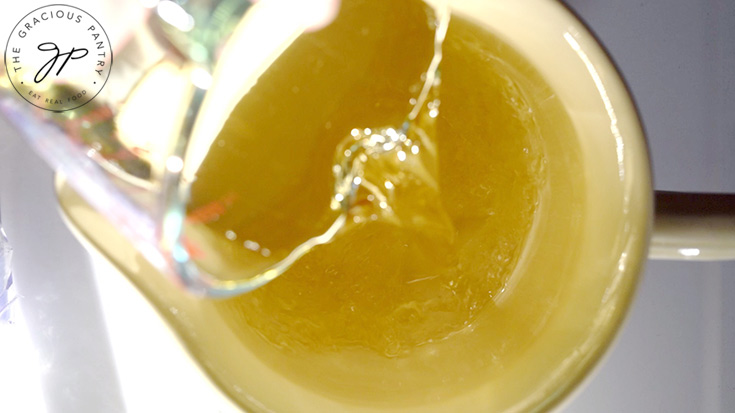 Pouring grape juice into a large, pale yellow pitcher.