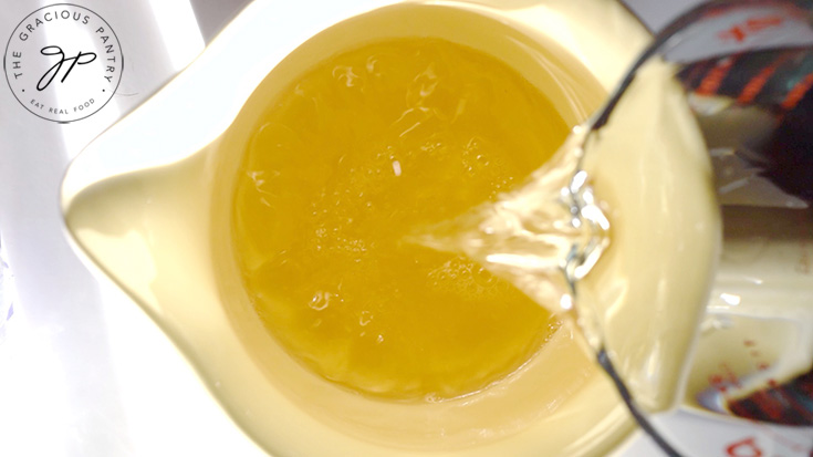 Pouring ginger ale into a large, pale yellow pitcher.