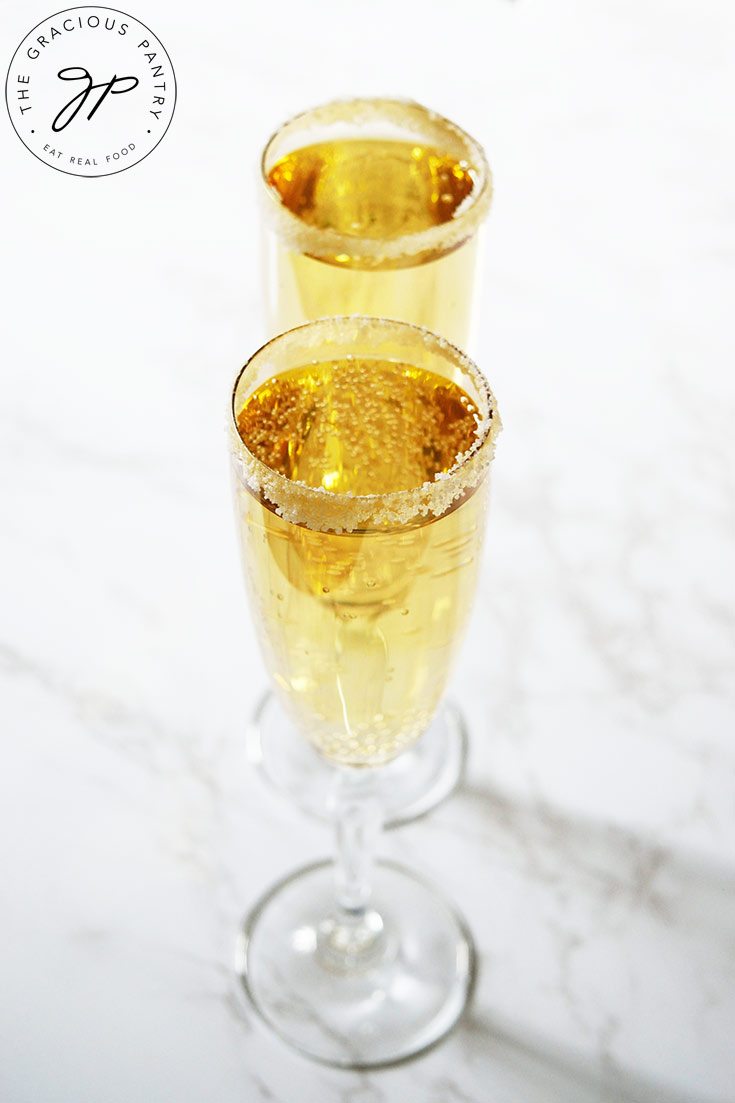 Two champagne glasses in a row, filled with Mock Champagne, on a white background.