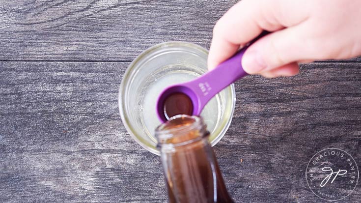 Measuring maple syrup into a canning jar.