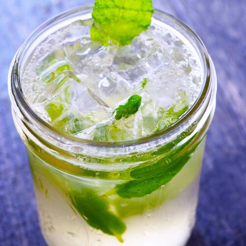 A mojito mocktail in a canning jar, garnished with a mint leaf.