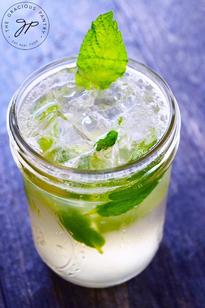 A mojito mocktail in a canning jar, garnished with a mint leaf.