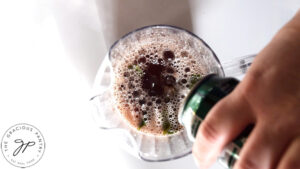 Pouring ginger ale from a can into a clear pitcher.