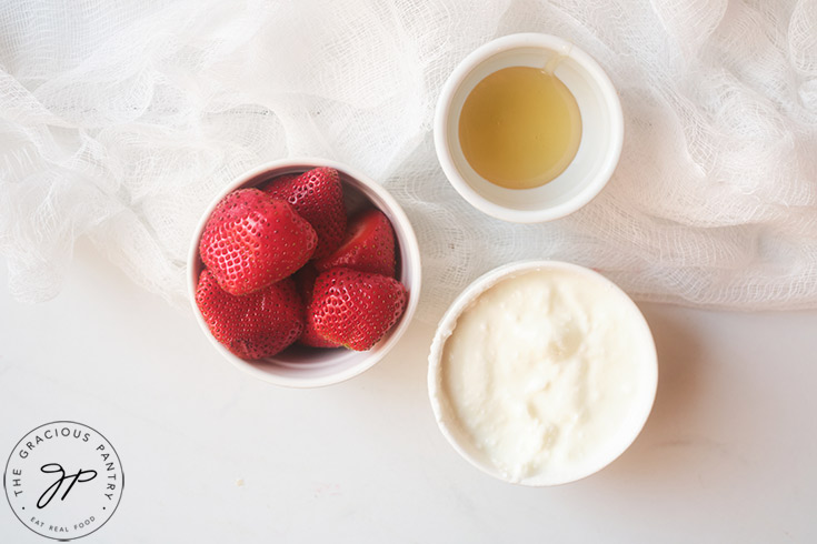 Three ingredients for this Strawberry Smoothie Recipe, in three different small, white bowls.